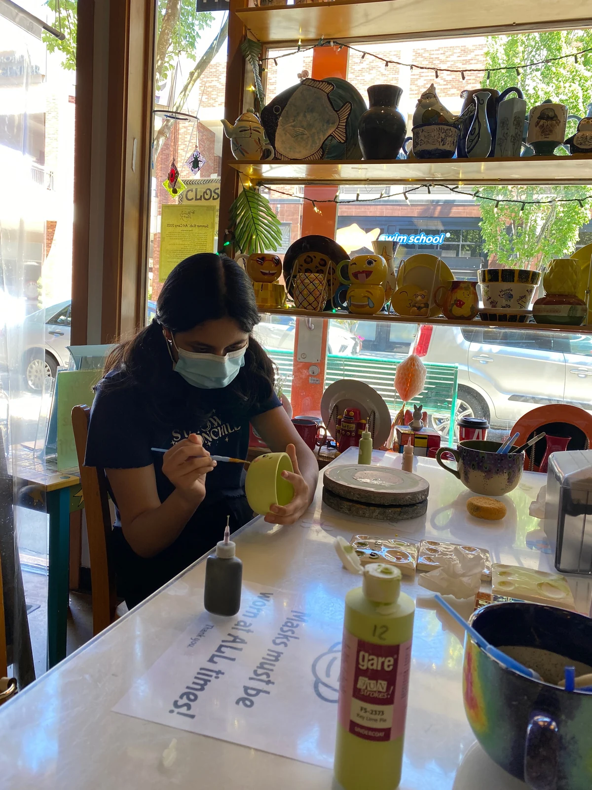 Mili painting a ceramic cup at a pottery studio.