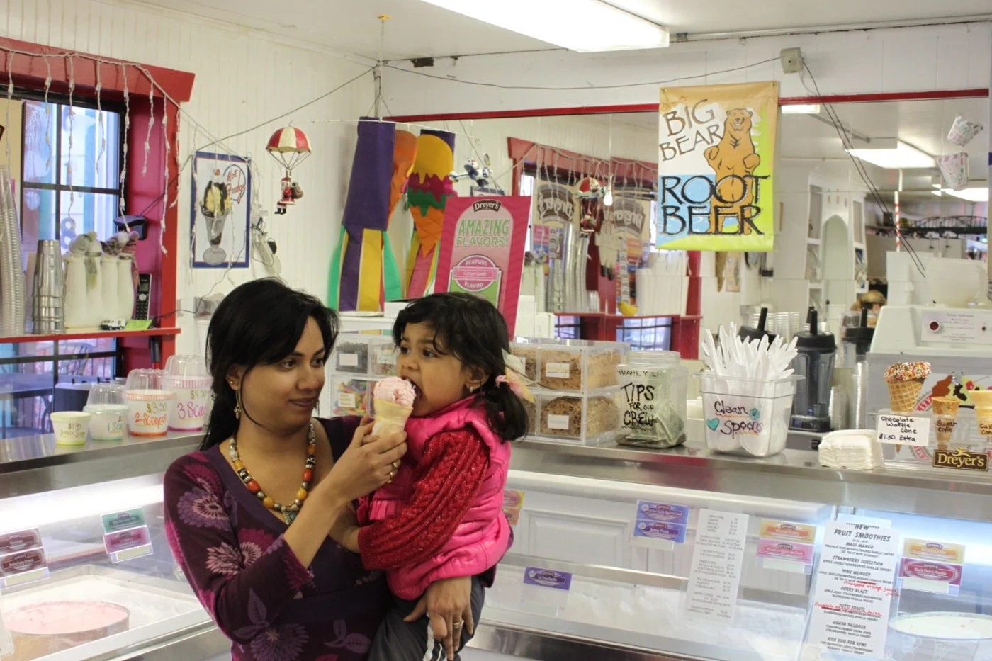 An adult holding a young child during a visit to a dessert shop.