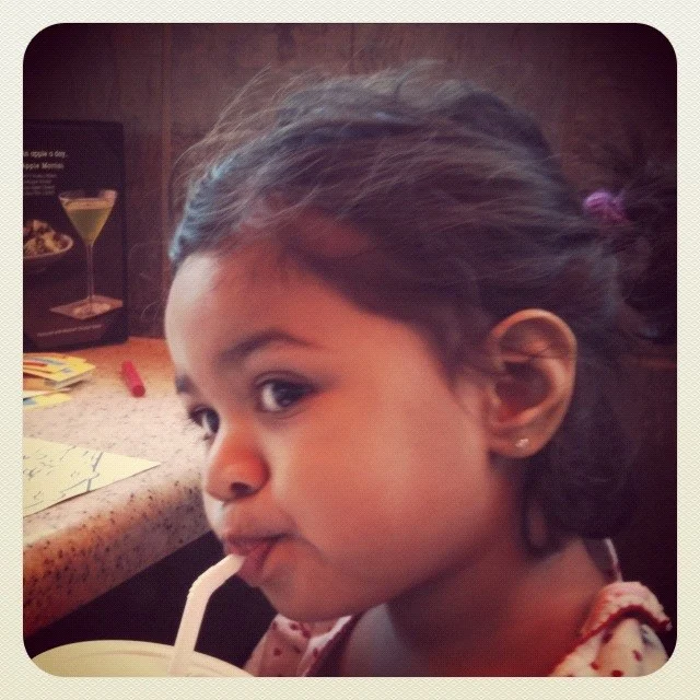 A close portrait of a child sipping through a straw.