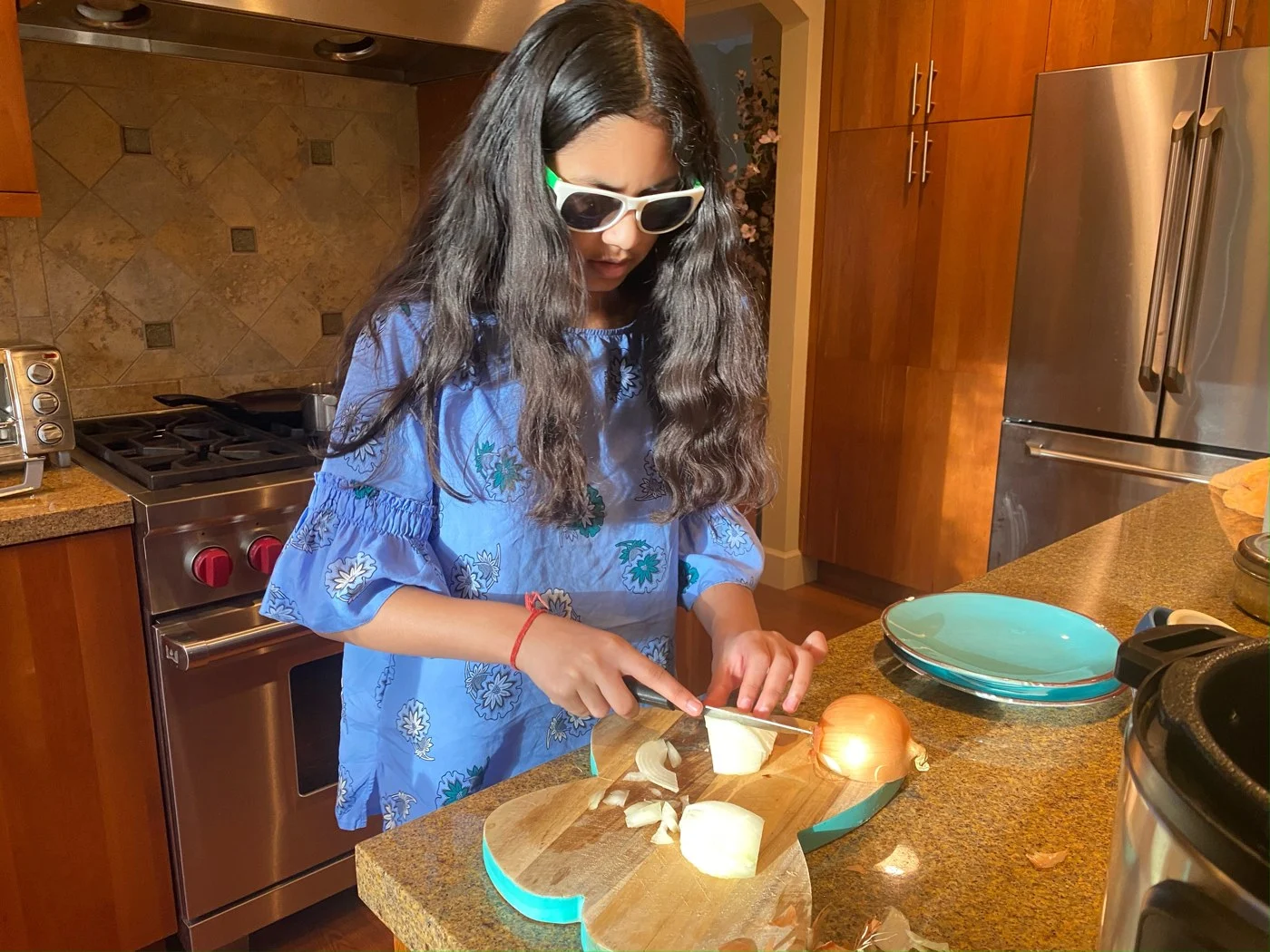 A young Mili preparing onions while wearing sunglasses
