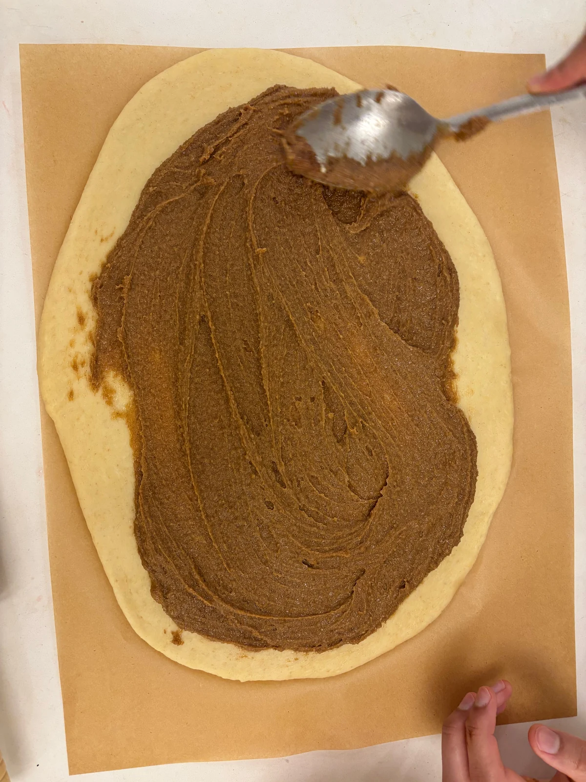Brown spread over a rolled oval/rectangle of pale dough; matches the following roll-making sequence.