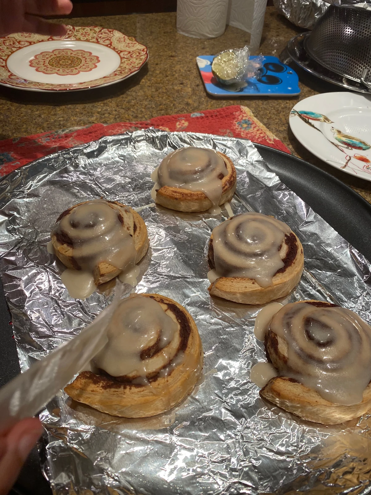 Individual flat spiral buns on foil with translucent pale glaze.