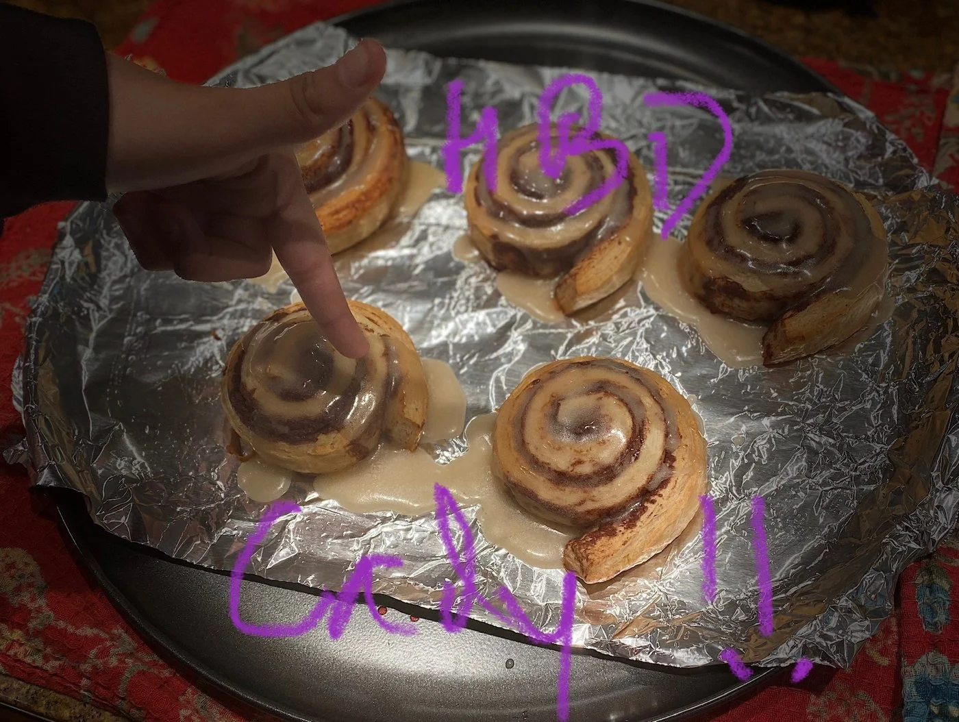 A glazed cinnamon-swirl tray with purple handwritten lettering across the photo.