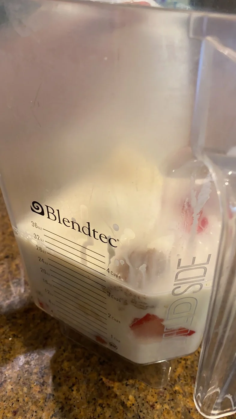 Unblended fruit and pale liquid visible through the side of a blender jar.
