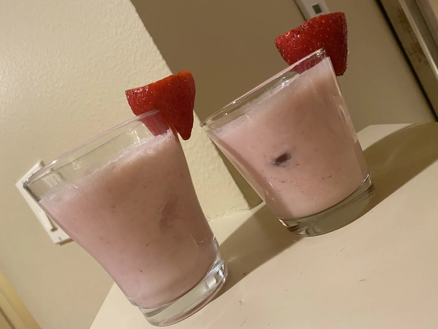 An angled view of two strawberry-garnished pink drinks.