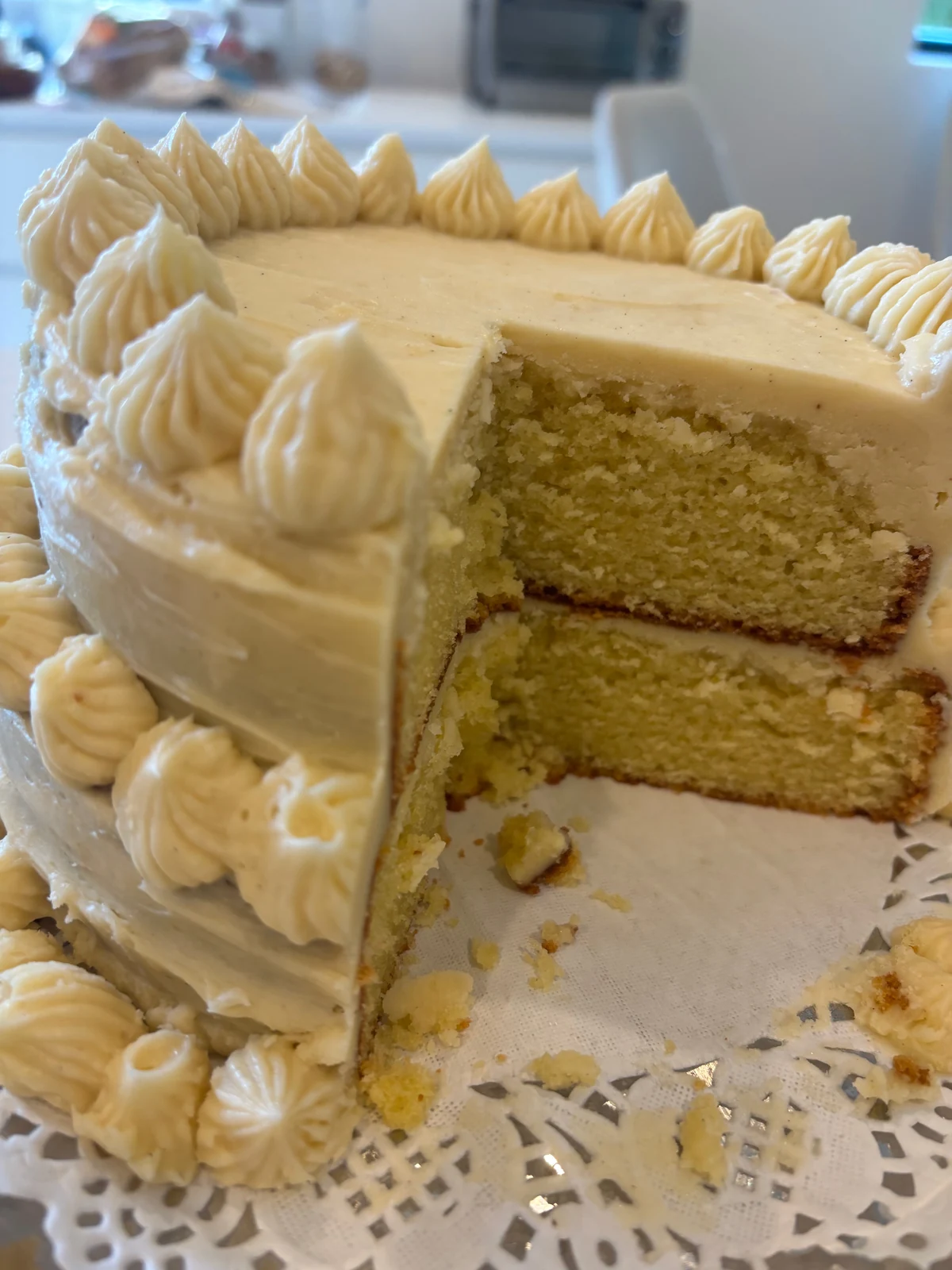 Another view of the two-layer yellow cake with piped pale frosting and a slice removed.