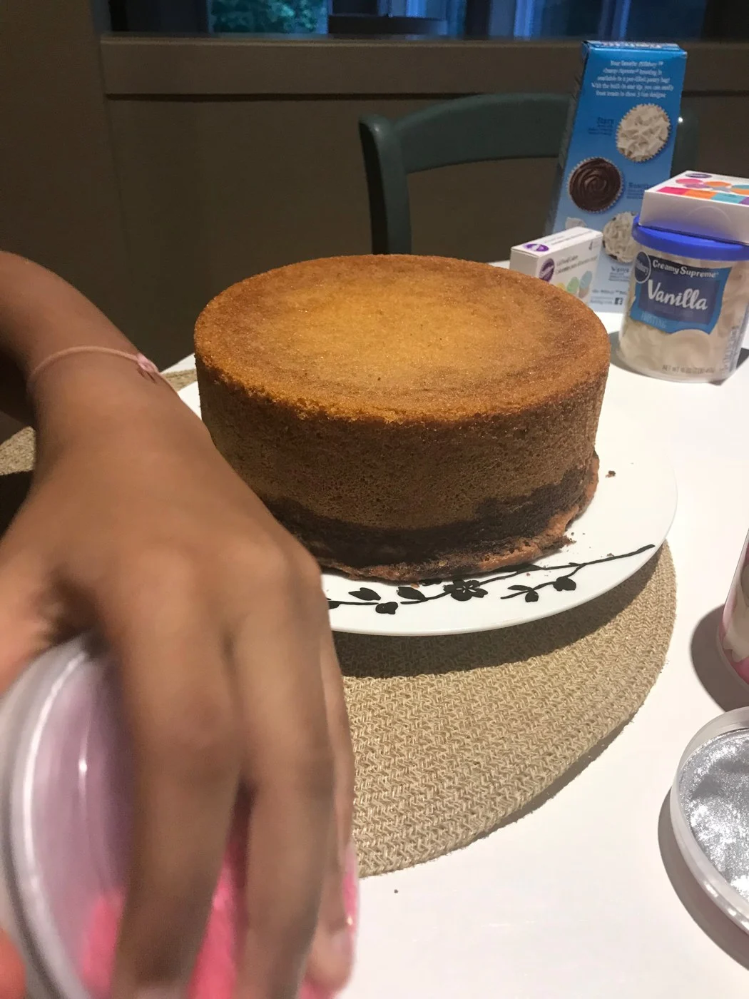 A golden round cake beside frosting supplies before decorating.