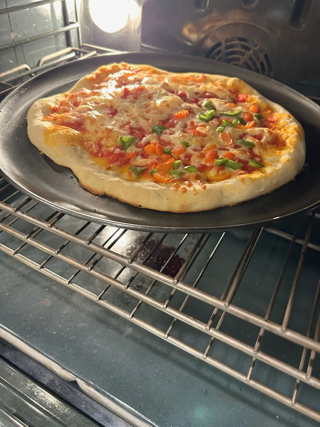 A vegetable-topped pizza baking on a tray inside the oven.